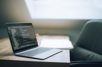 Laptop displaying code on a wooden table.