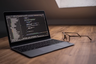 Laptop displaying code with glasses on desk