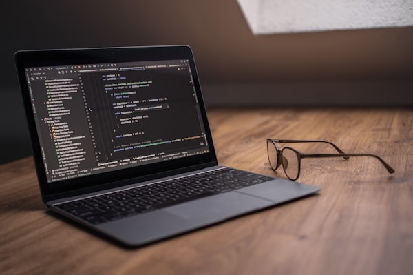 Arbeitsplatz mit Laptop und Brille auf einem Tisch
