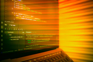 Laptop screen displaying code with orange glow.