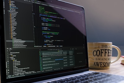 Laptop screen displaying code with a coffee mug.
