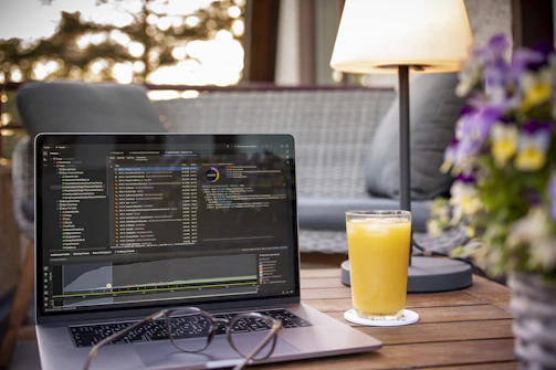 Laptop with code and orange juice on table