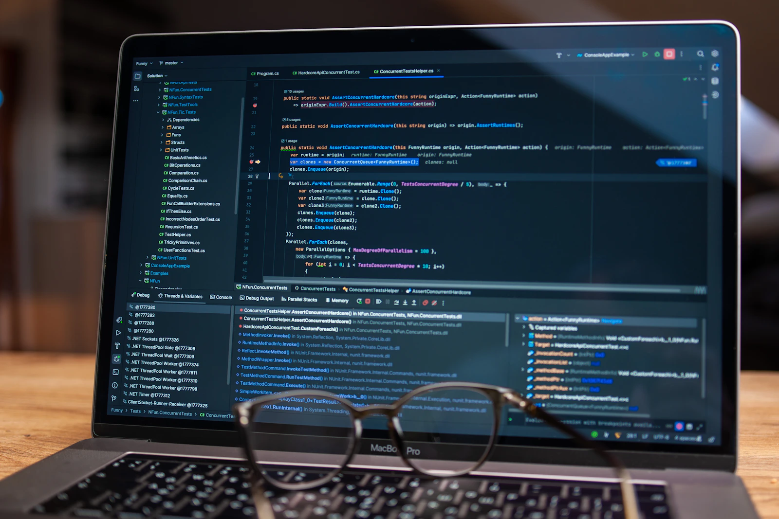 Notebook com código na tela e óculos sobre a mesa
