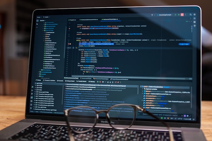 Laptop screen with code and glasses on a desk — close inspection of encoded text