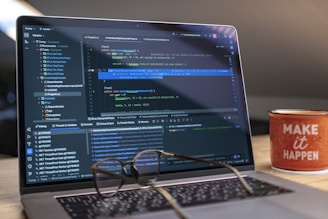 Laptop screen displaying code with glasses and mug.