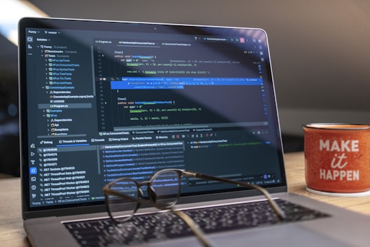 Laptop screen displaying code with glasses and mug.