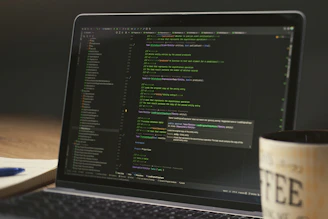 Laptop screen displaying lines of code with a coffee mug.