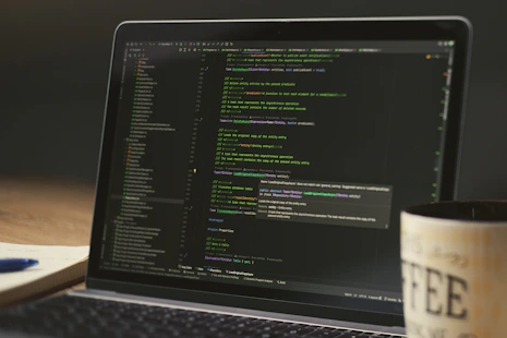 Laptop screen displaying lines of code with a coffee mug.