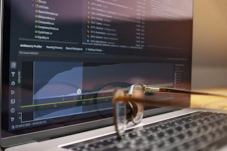 Laptop screen displaying code and graphs with glasses on keyboard
