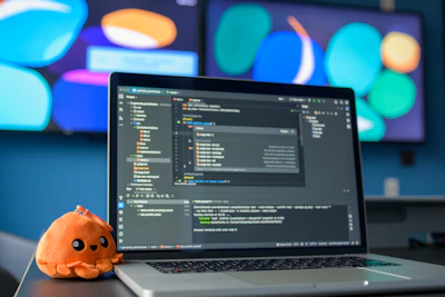 Laptop with code and a small plush octopus.