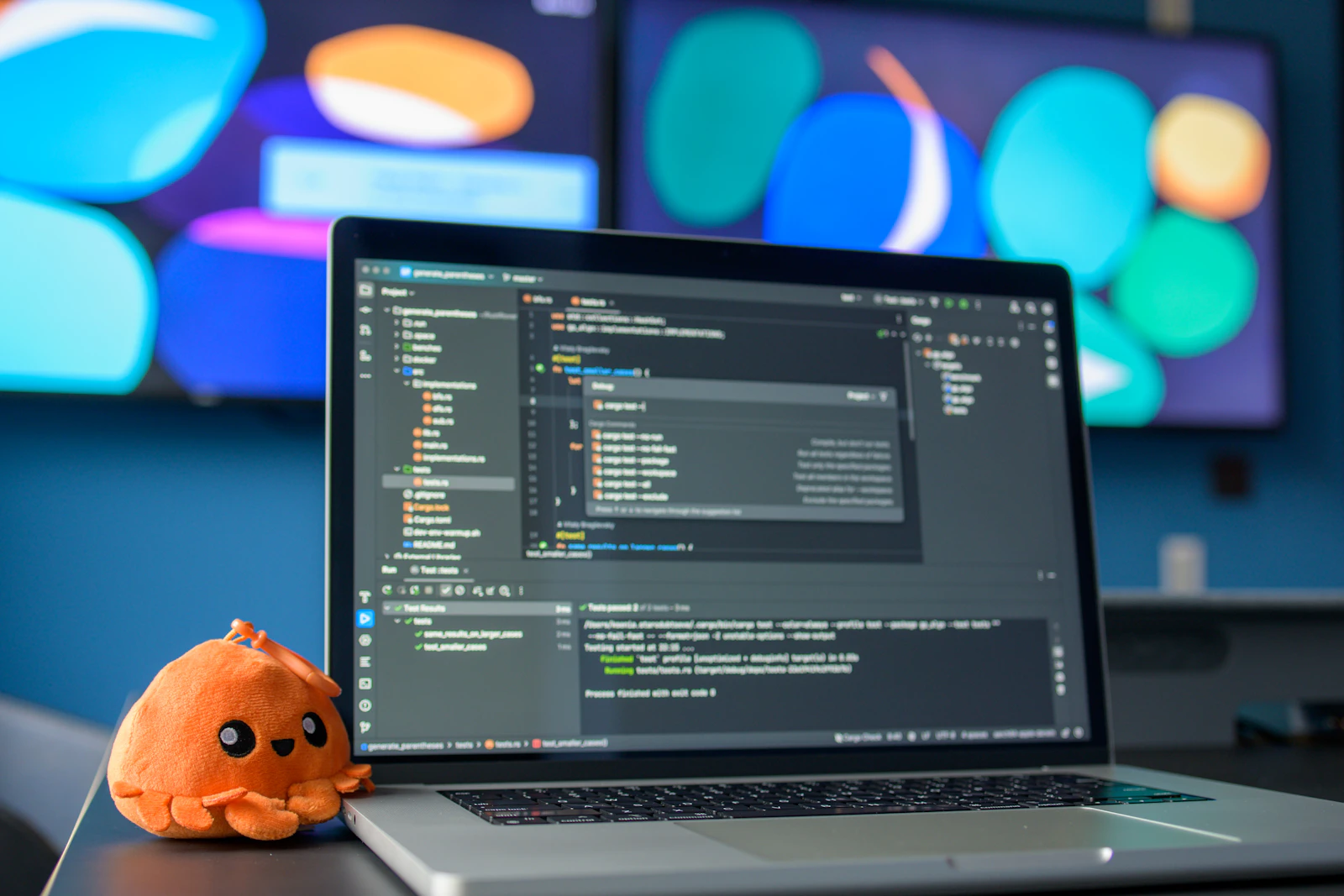 A laptop displaying code beside a small plush octopus