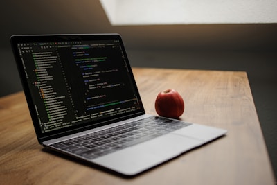 Laptop displaying code with an apple nearby