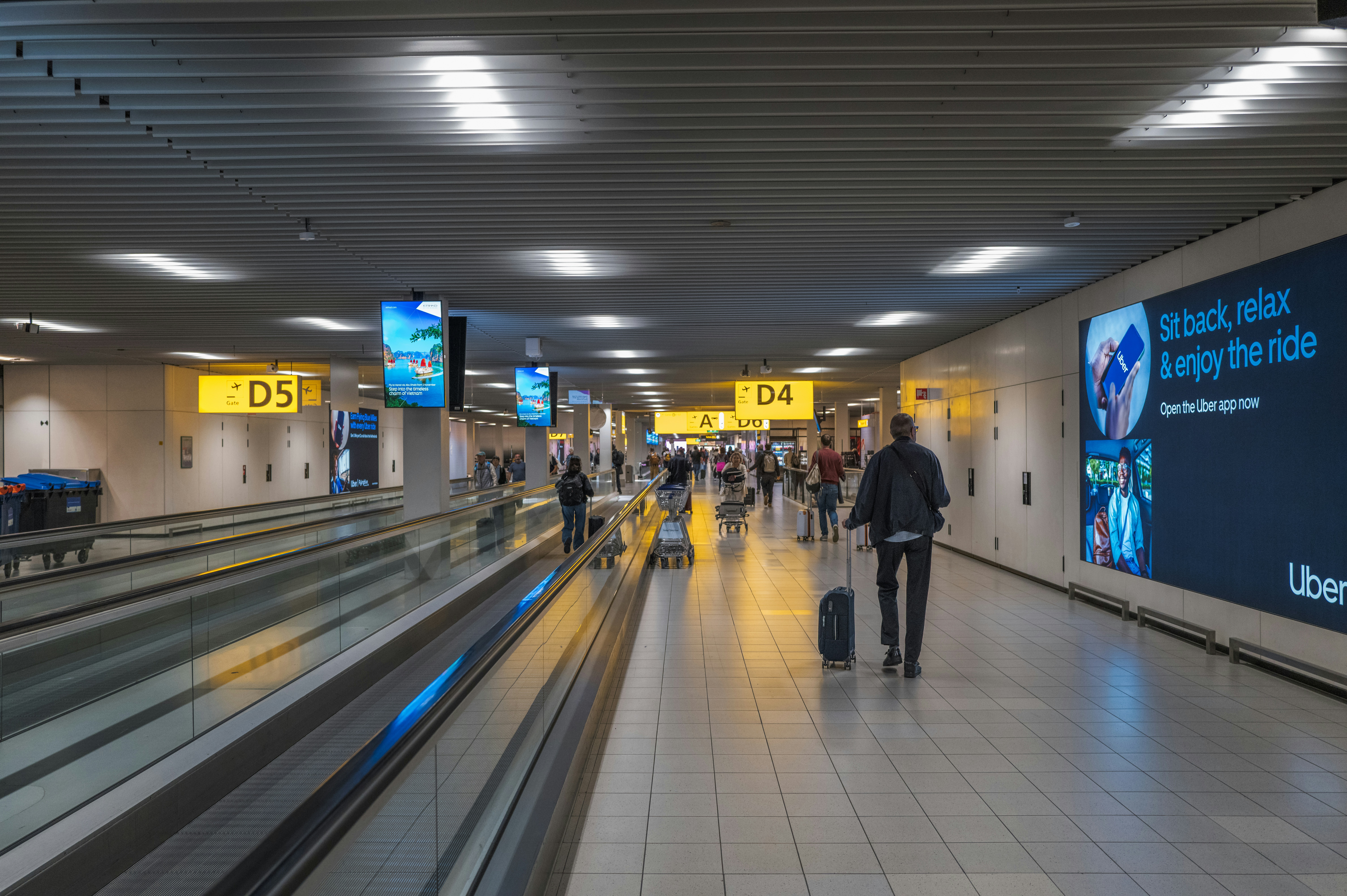 People walking in a modern airport terminal with moving walkways.
