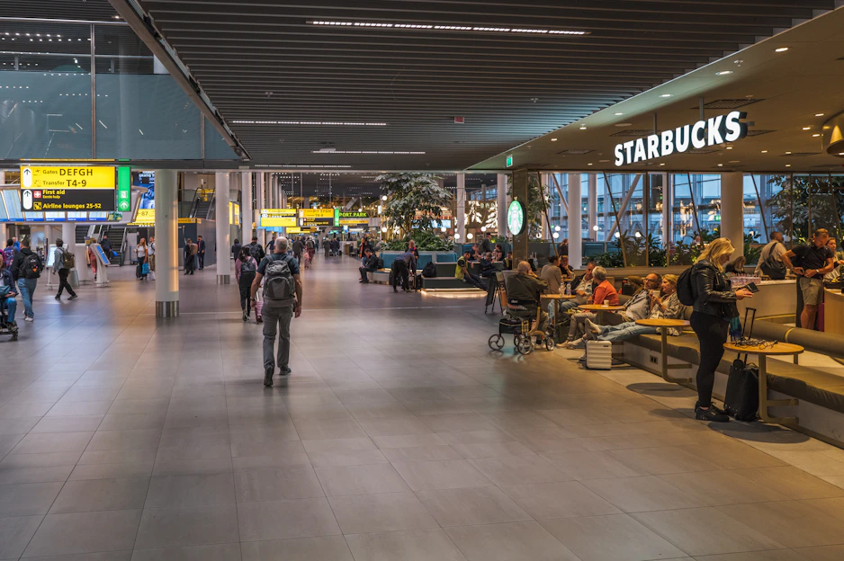 People at a starbucks in a modern airport terminal.