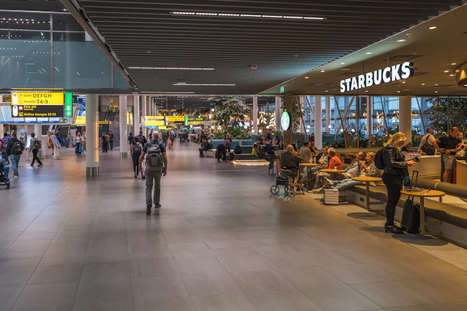 People at a starbucks in a modern airport terminal.