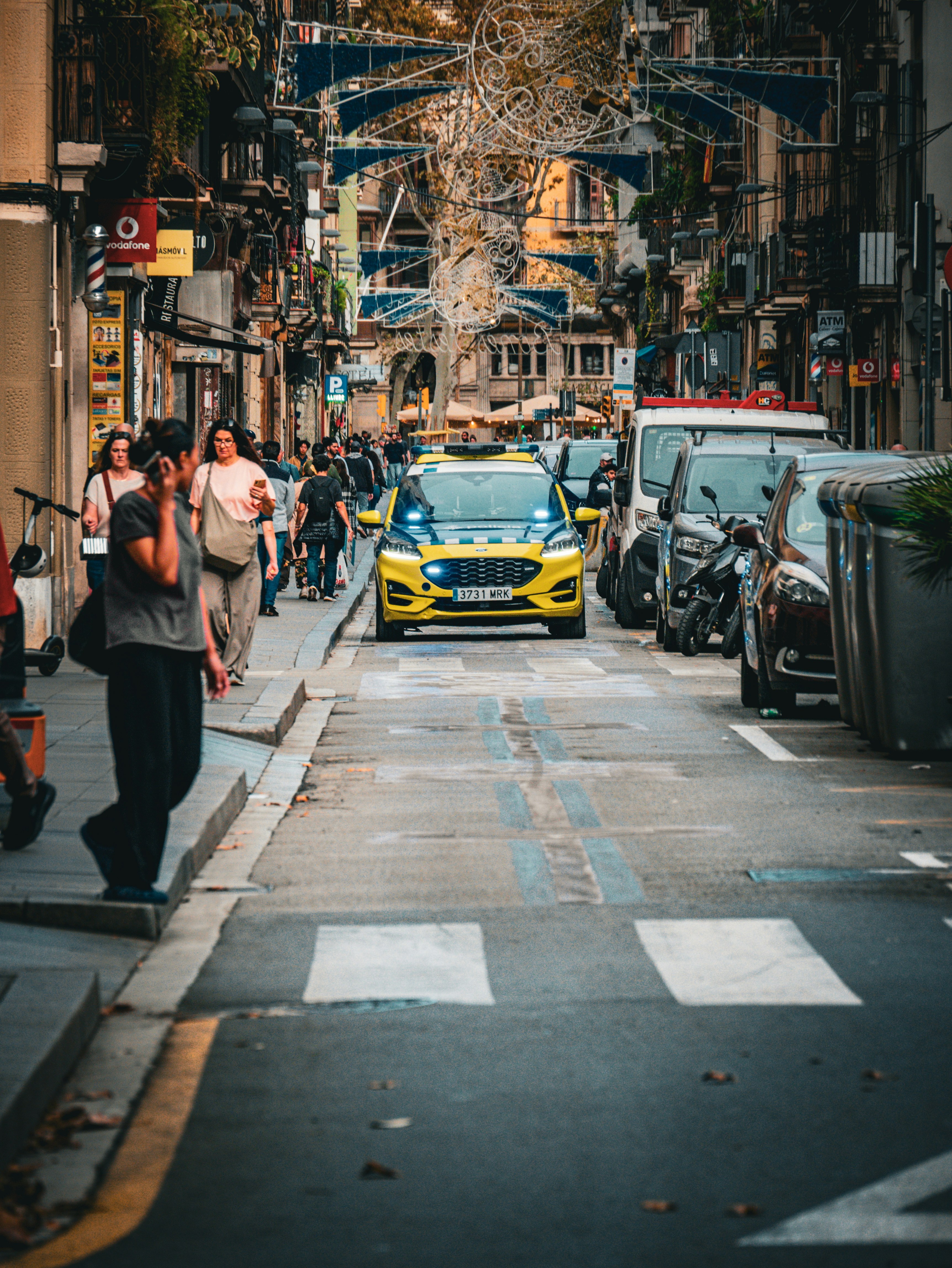 Yellow police car on a busy city street.