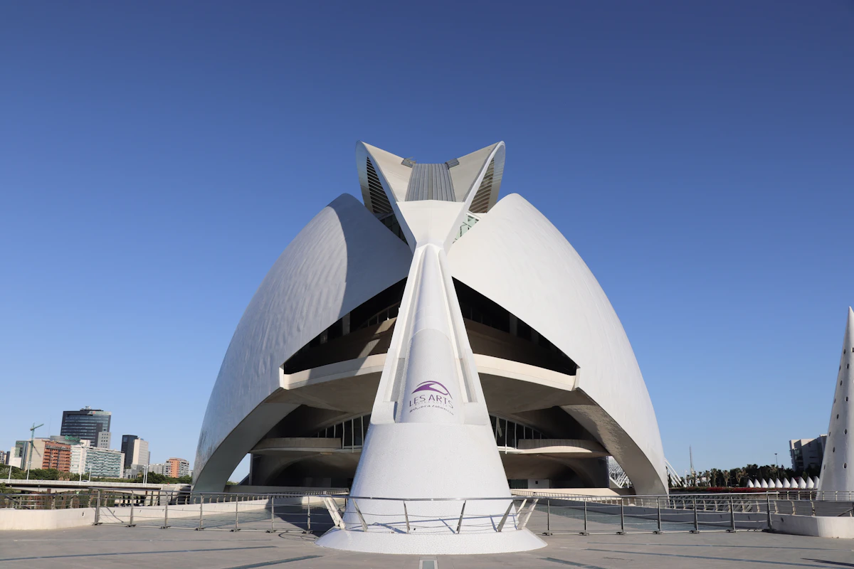 Symmetrical white concrete shells curving against a clear sky, futurist architecture