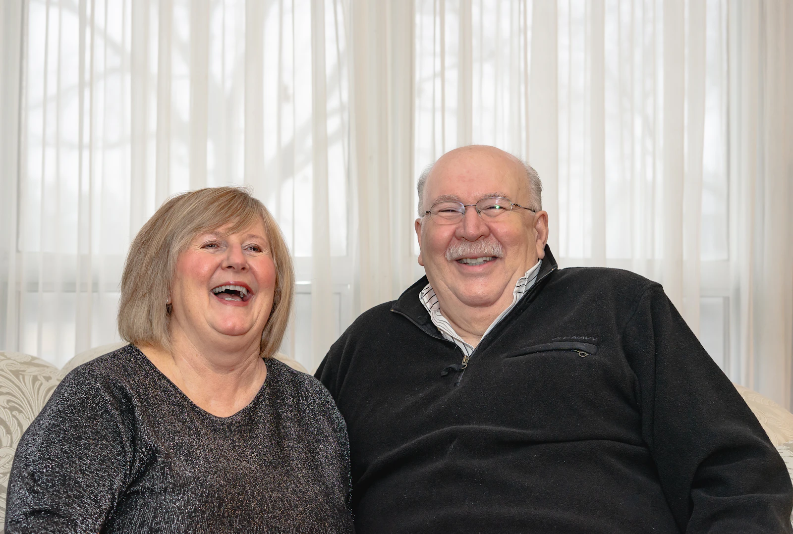 Happy older married couple laughing together at home