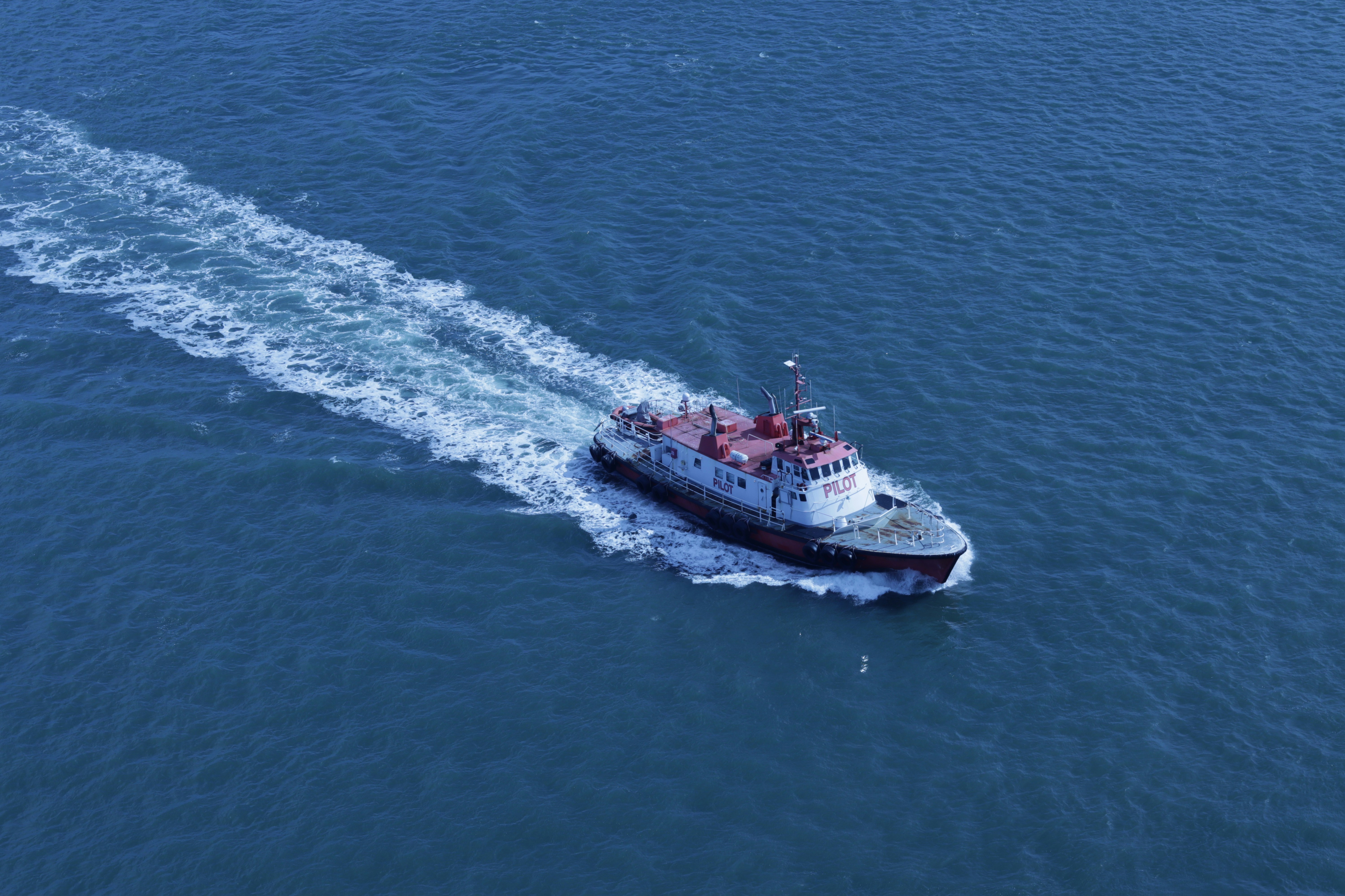 A small boat speeds across the blue ocean.