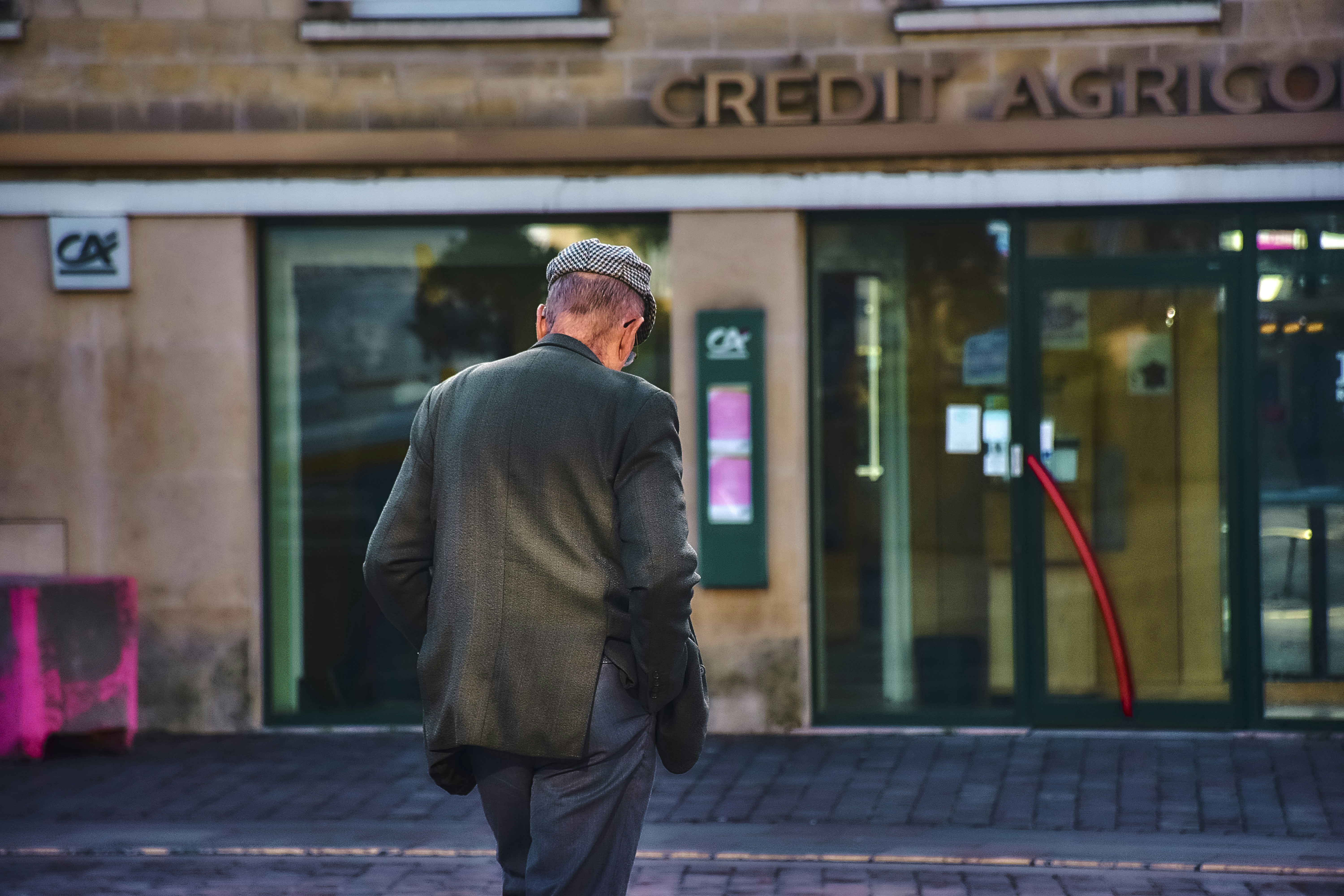 A long queue of people waiting outside an ATM, with some looking frustrated. In the background, a 'Bank Closed' sign is visible on a bank door.