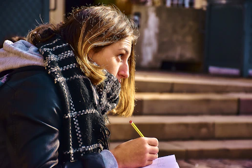 Étudiante qui réfléchit au sujet de son mémoire en prenant des notes