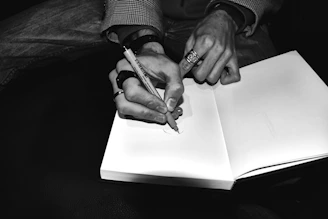 Hands writing in a blank book with a pen
