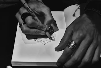 Hands drawing a design in a sketchbook