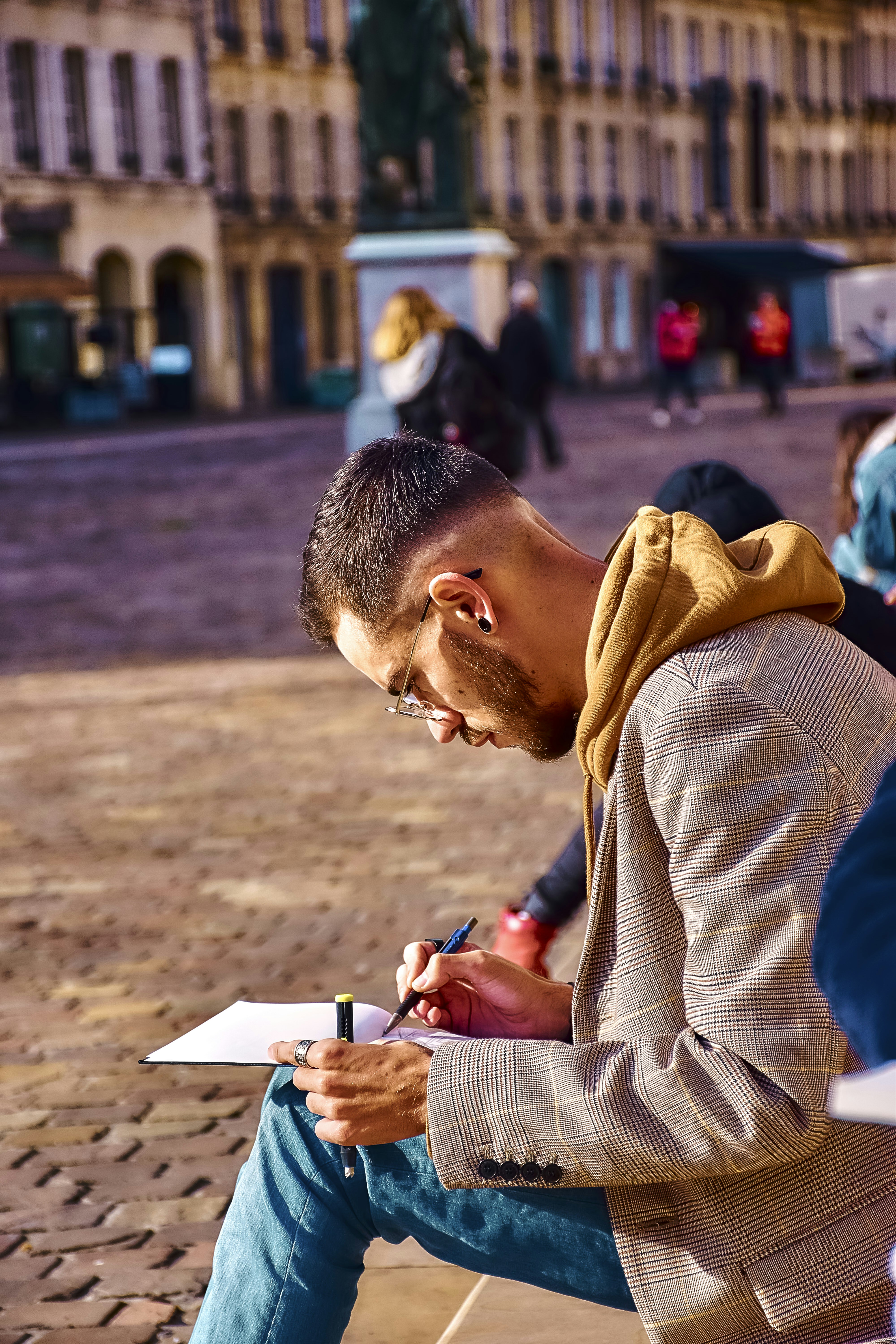 Man sketching on paper in a city square.