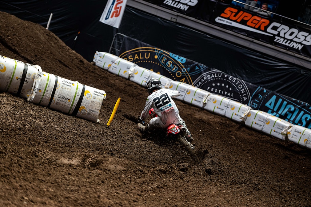 Motocross rider charging down a steep muddy dirt track