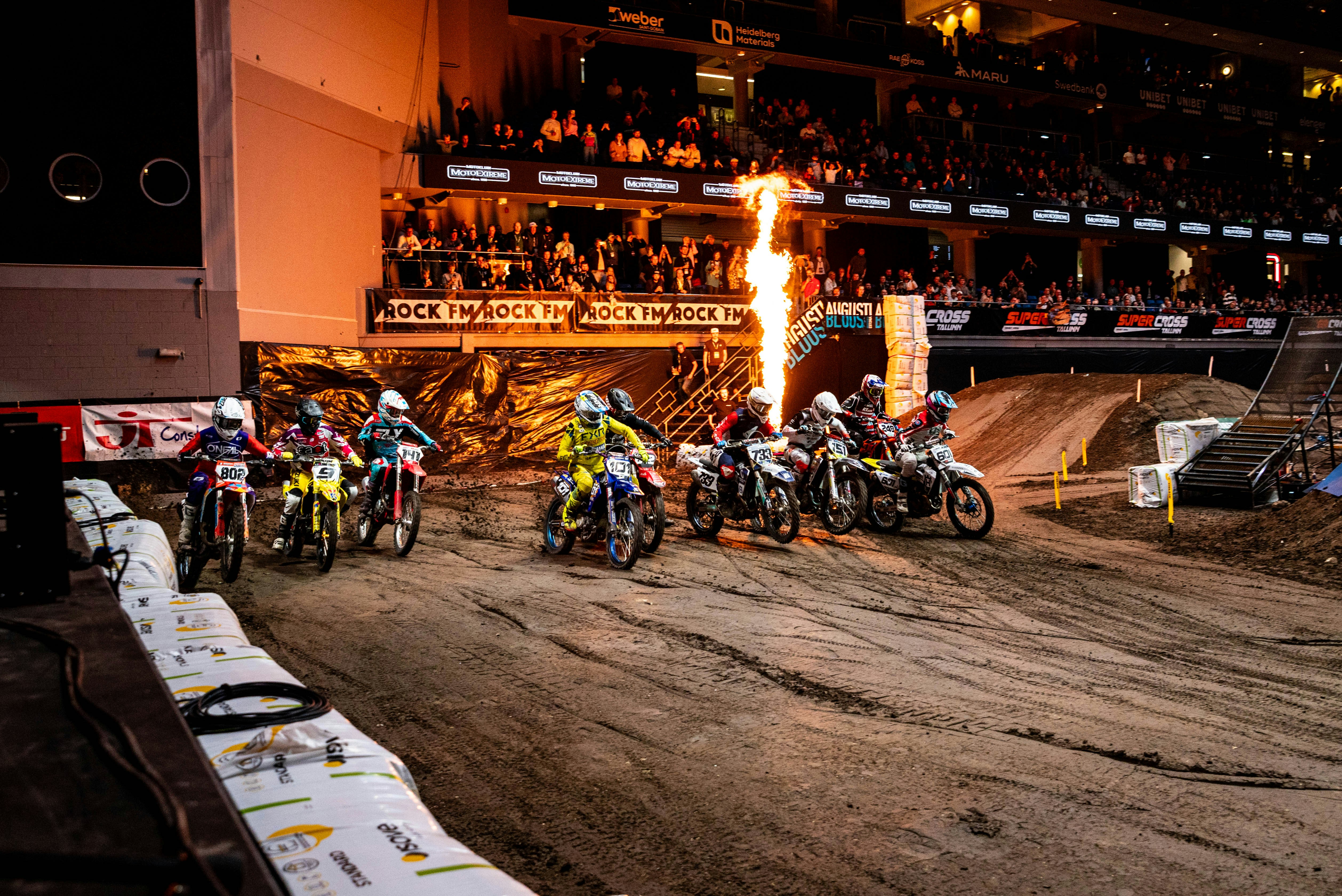Motocross racers on dirt track with flames