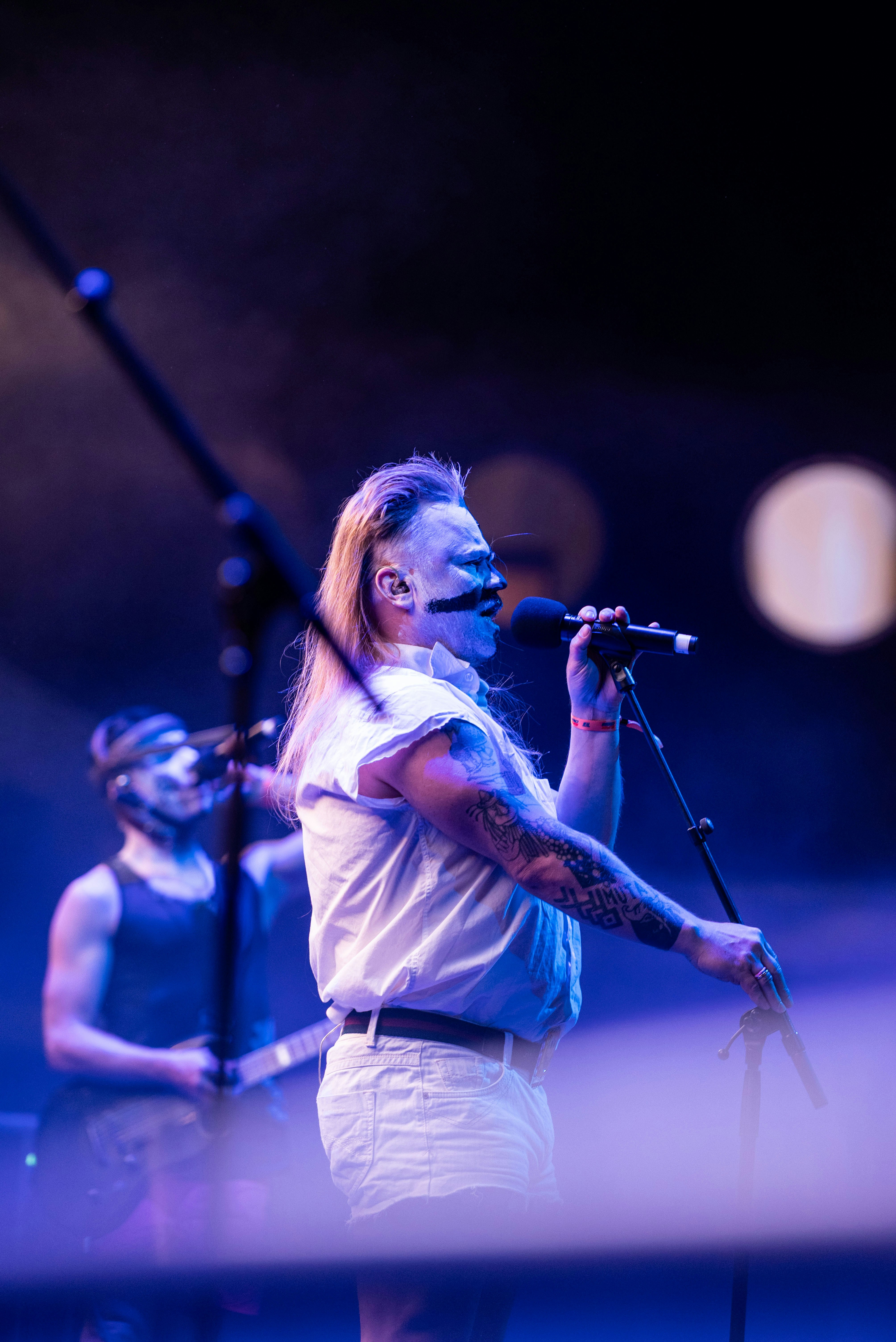 Singer performing with microphone on stage with band.