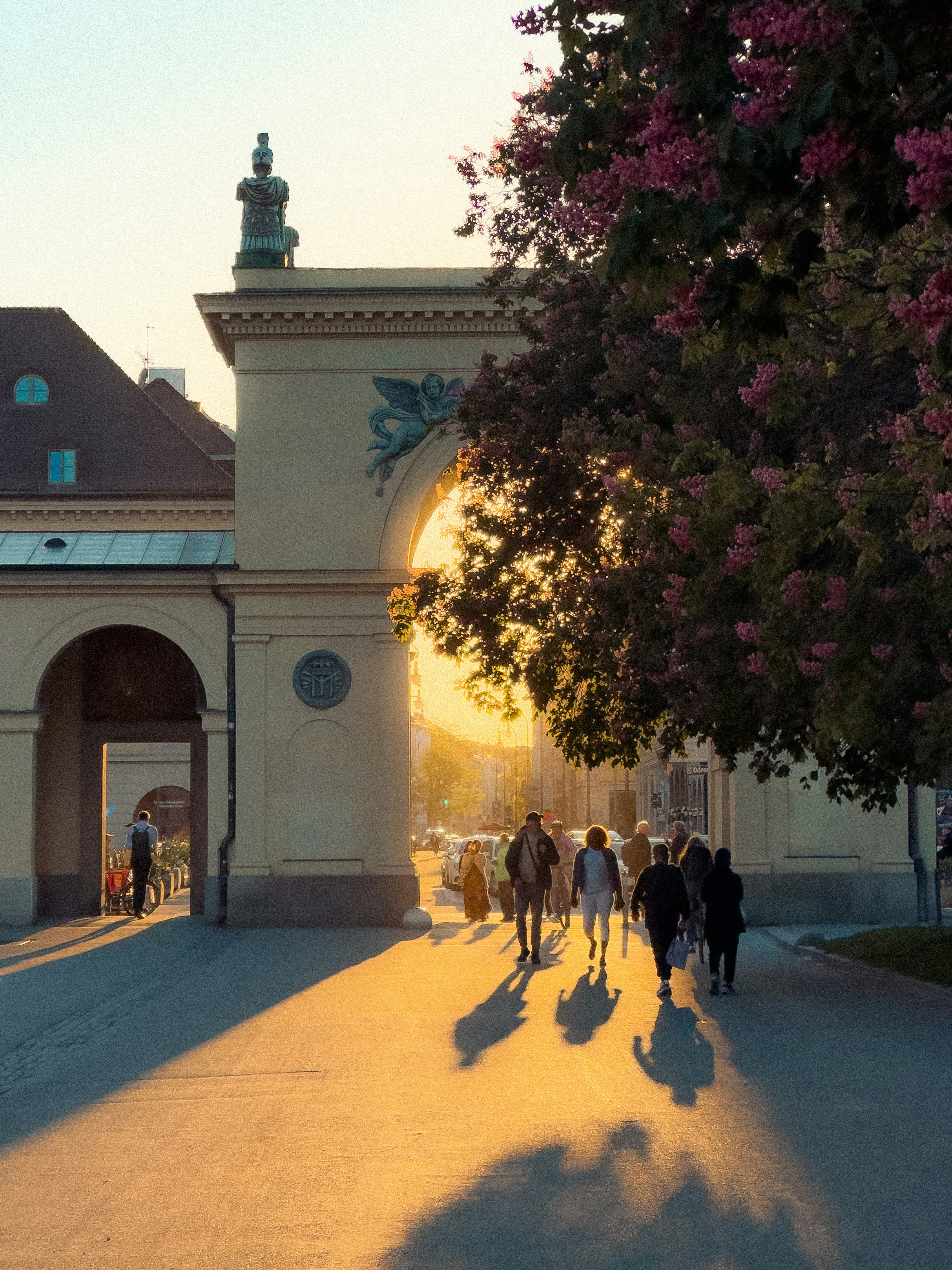 People walk towards a sunlit archway at sunset.
