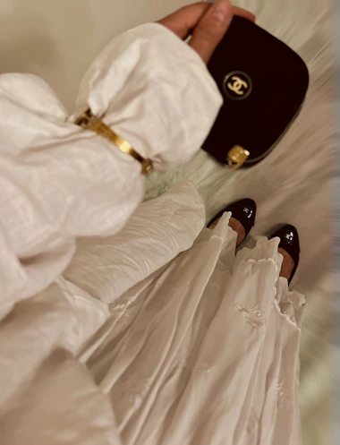 Woman in white dress holding a dark handbag