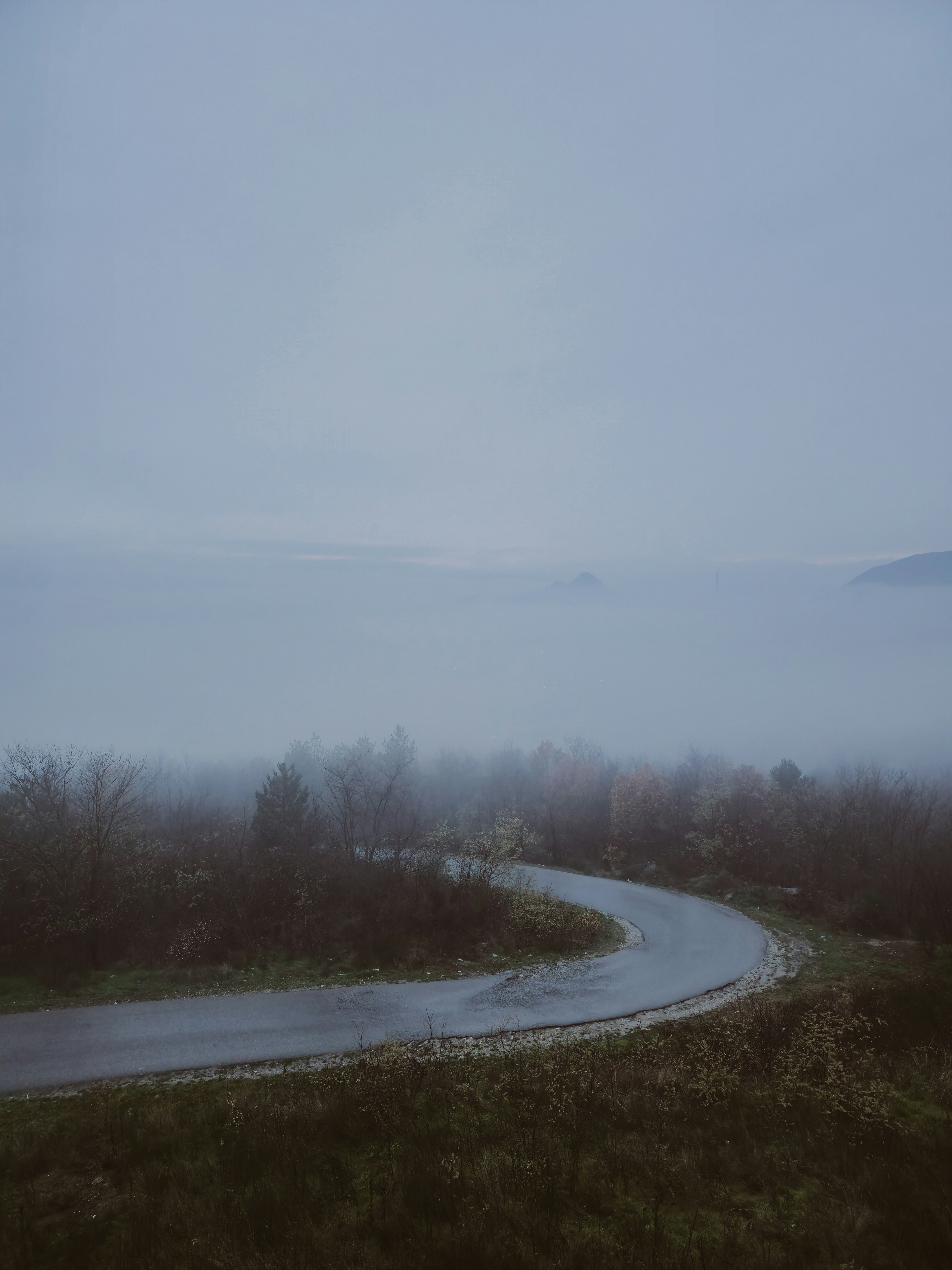 A winding road through a misty, overcast landscape.