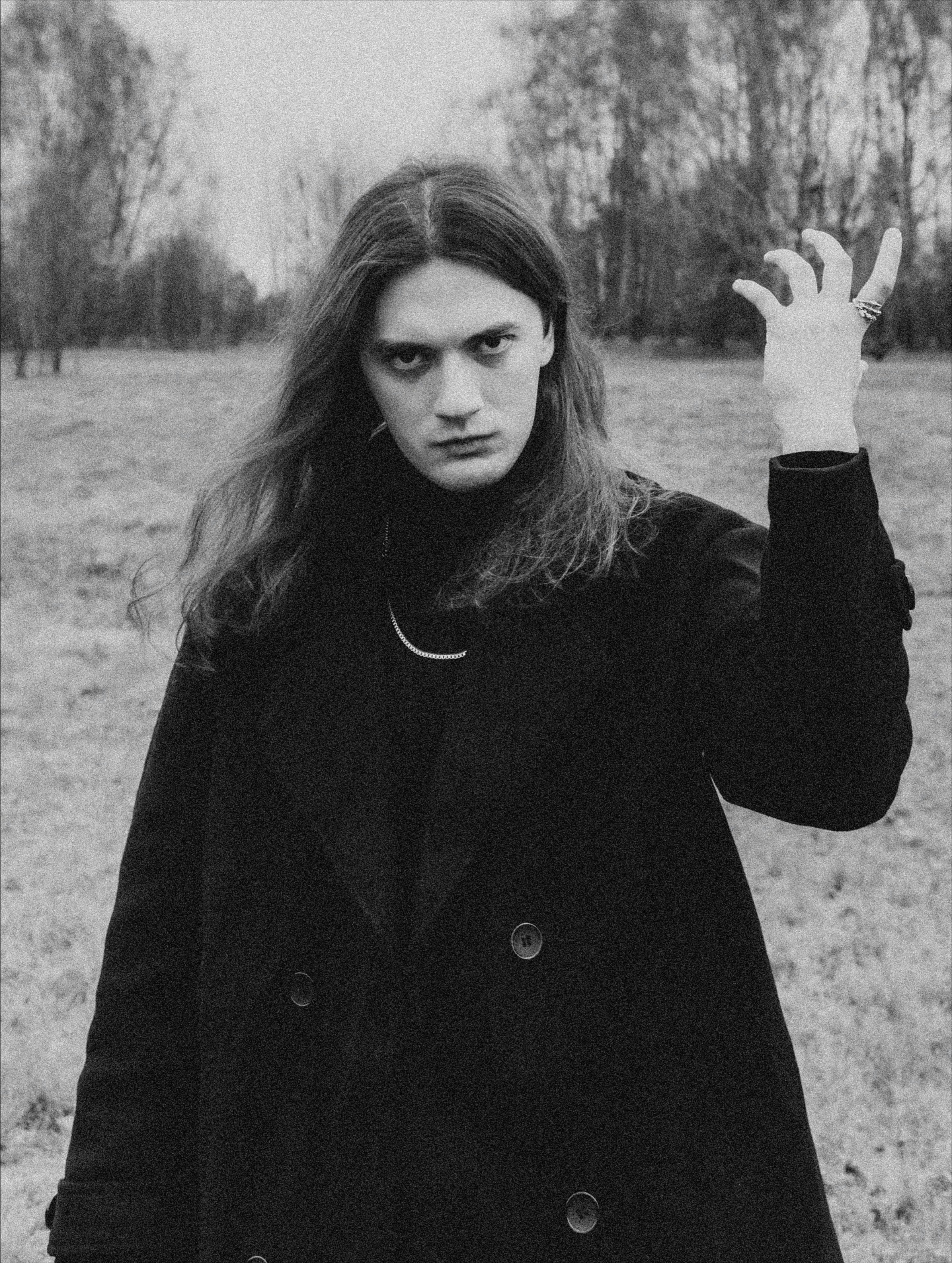 A man with long hair in a black coat