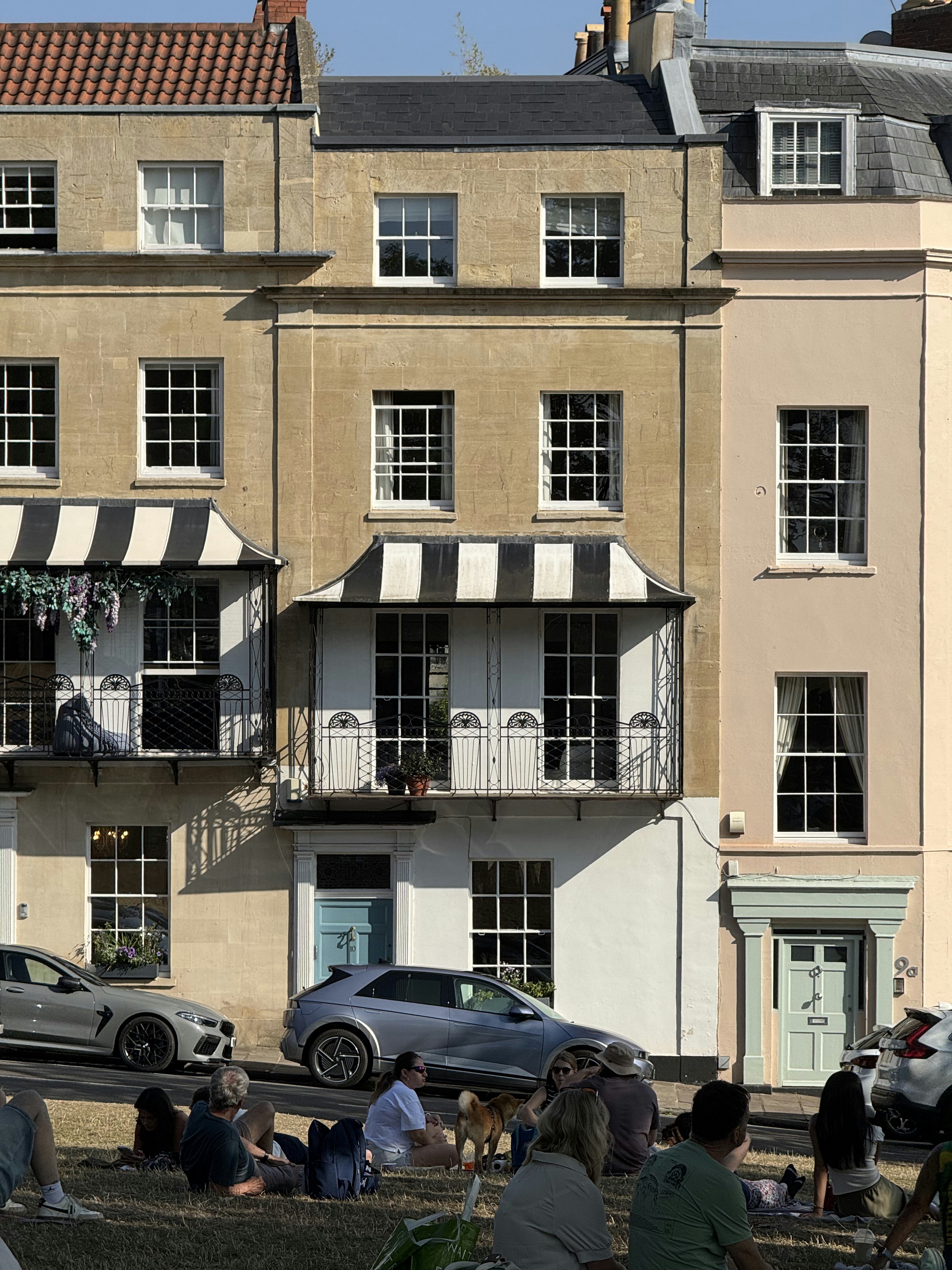 People relaxing on grass in front of townhouses