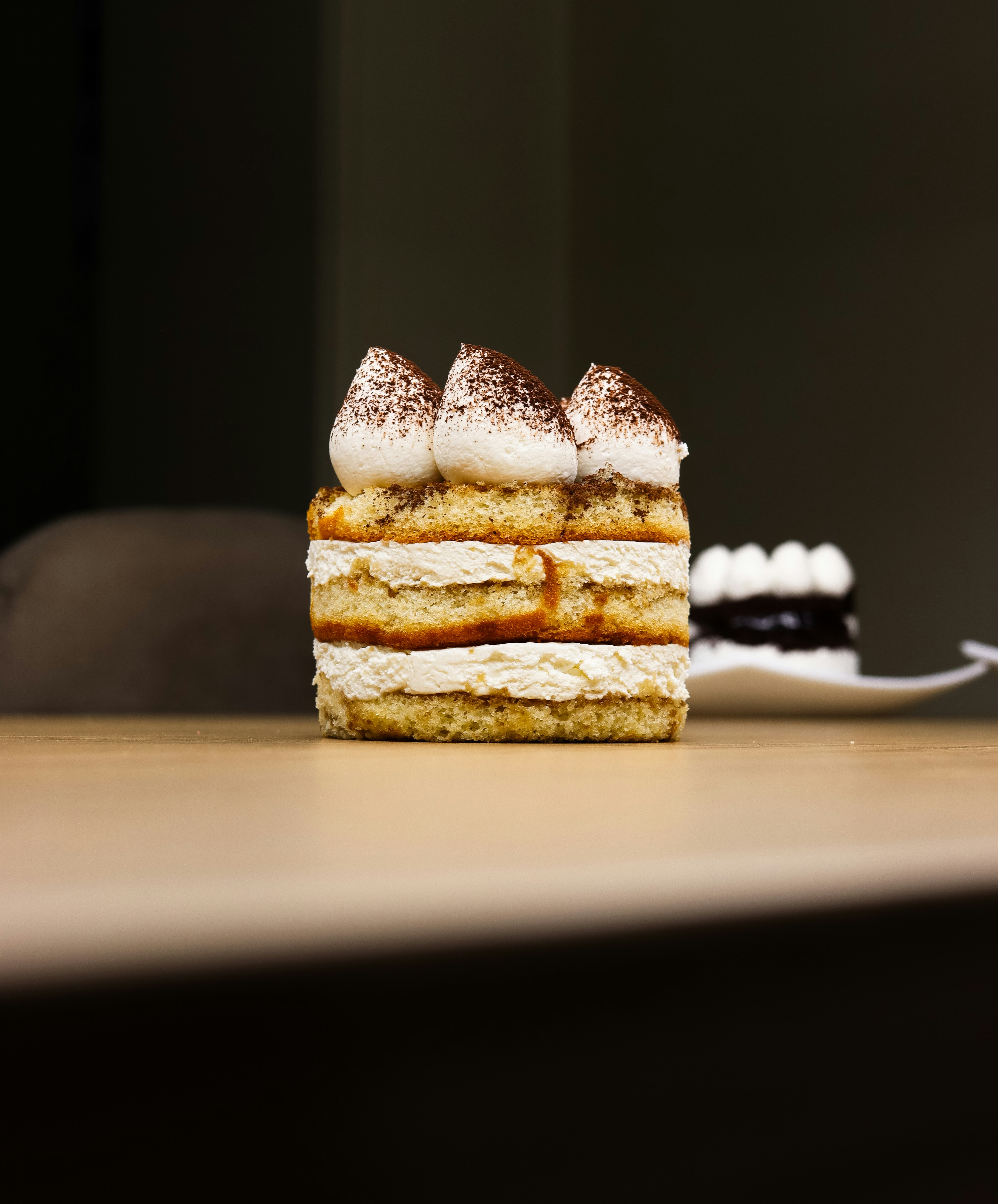 A layered tiramisu cake with whipped cream and cocoa