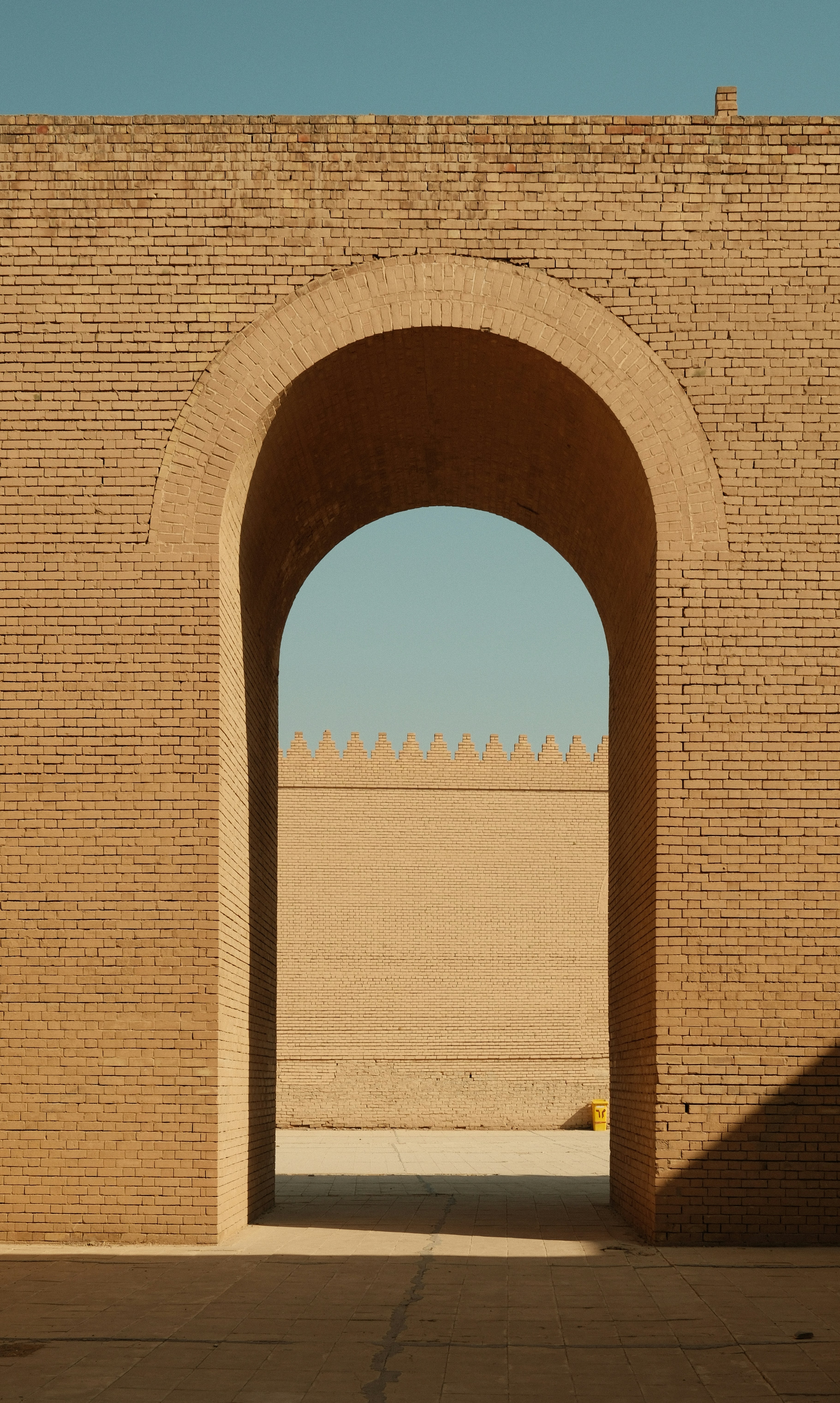 Ancient brick archway with crenellated wall beyond