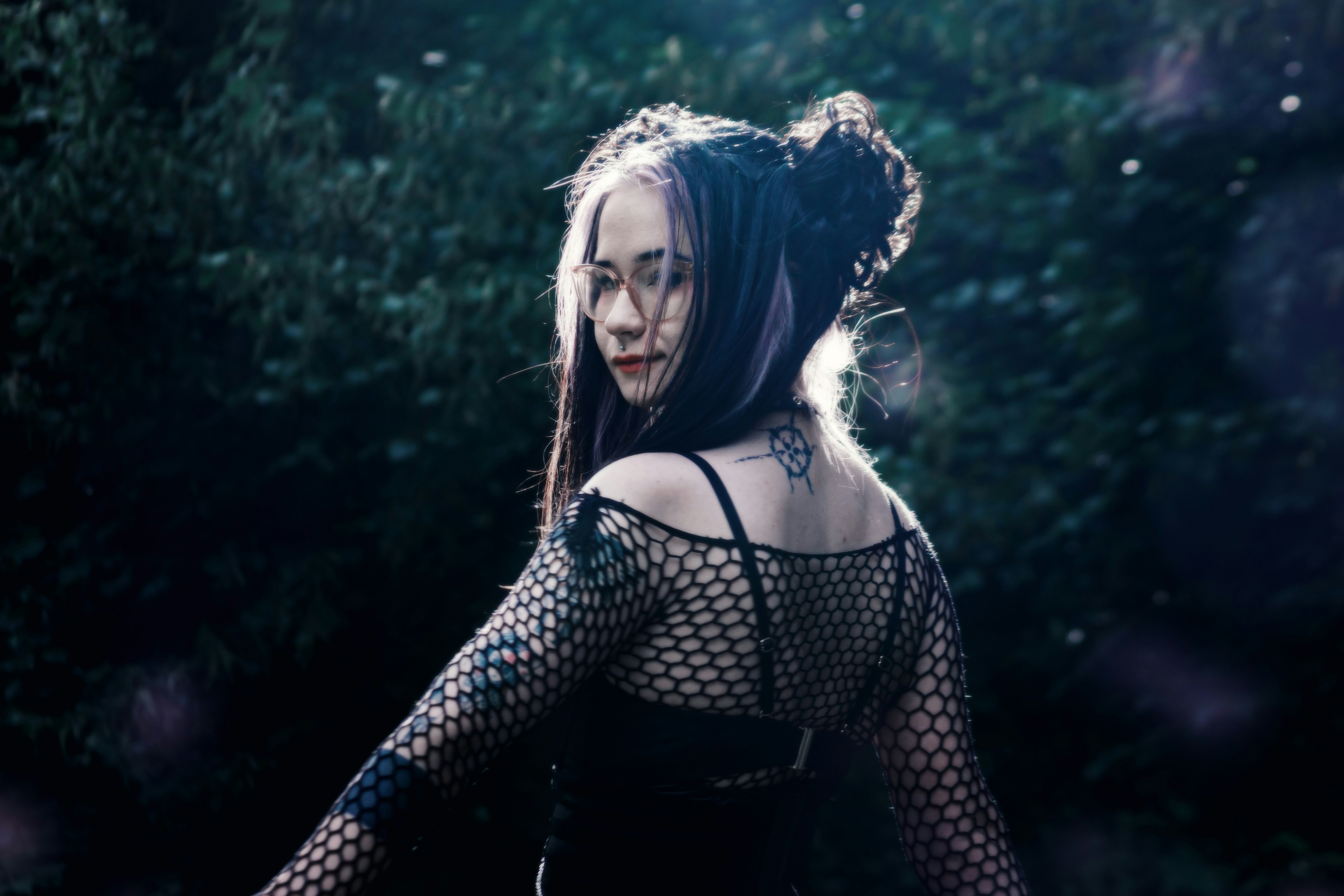 Young woman with tattoos in a dark forest