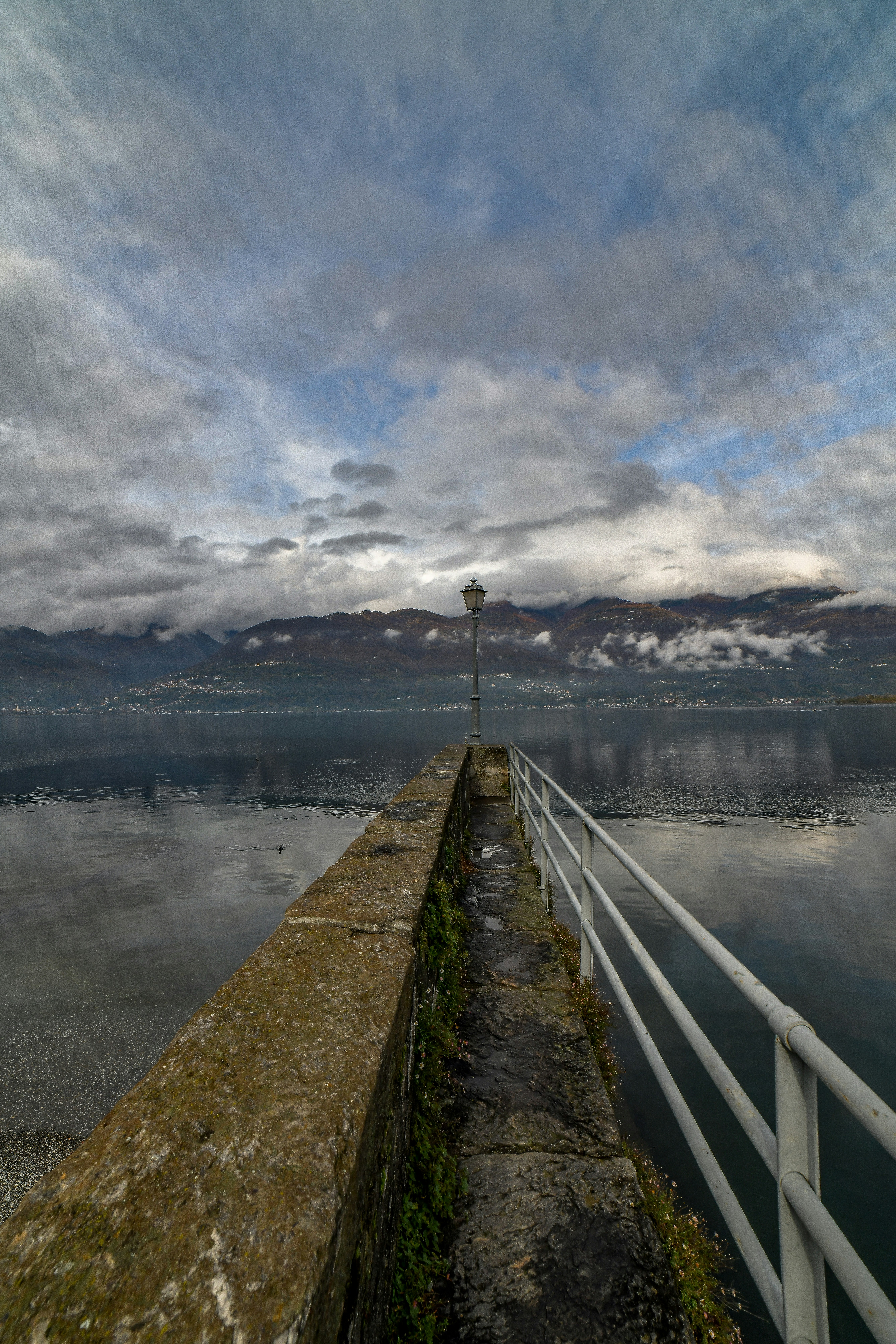 Stone pier with railing leading to distant mountains