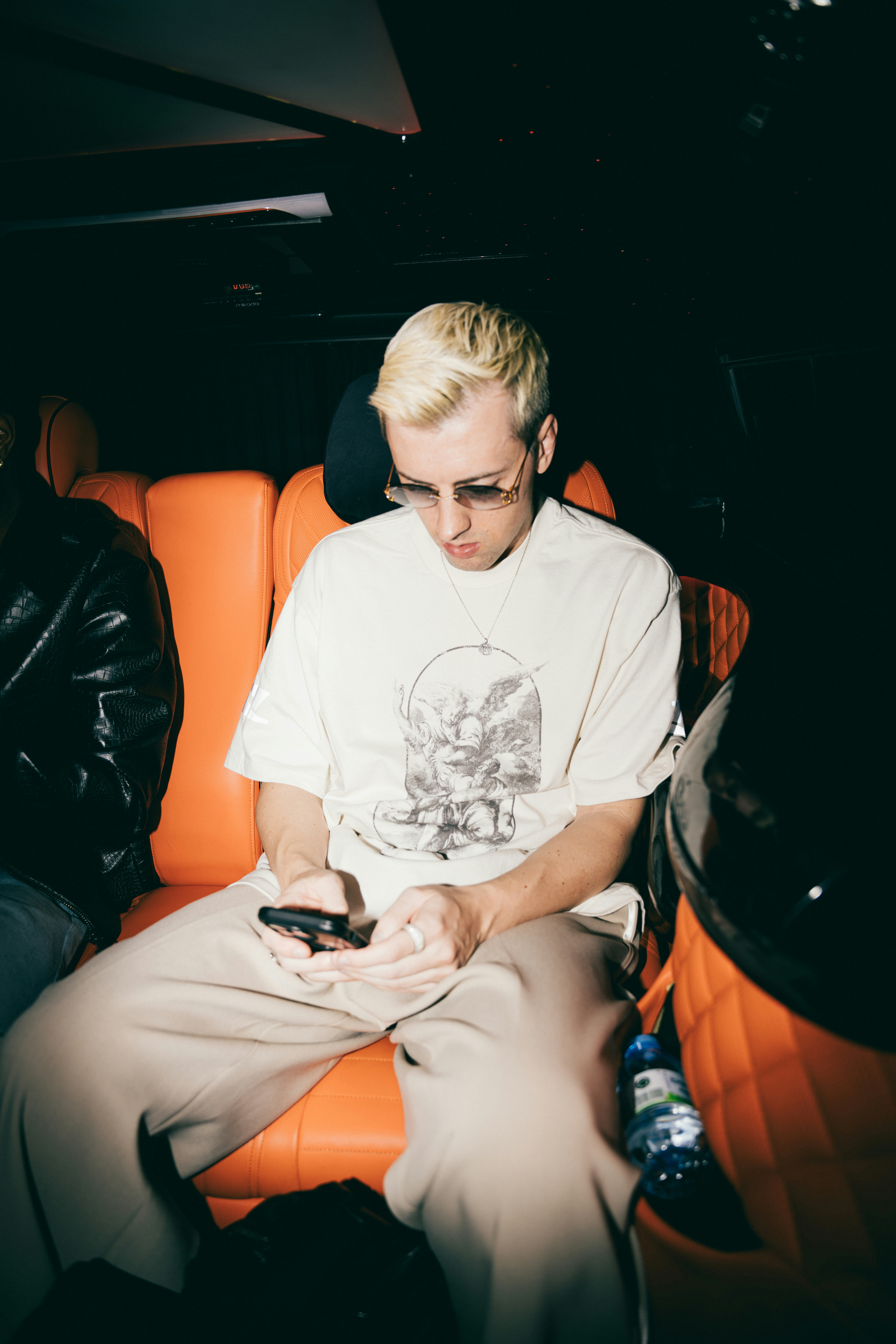 Man with blonde hair using phone in car