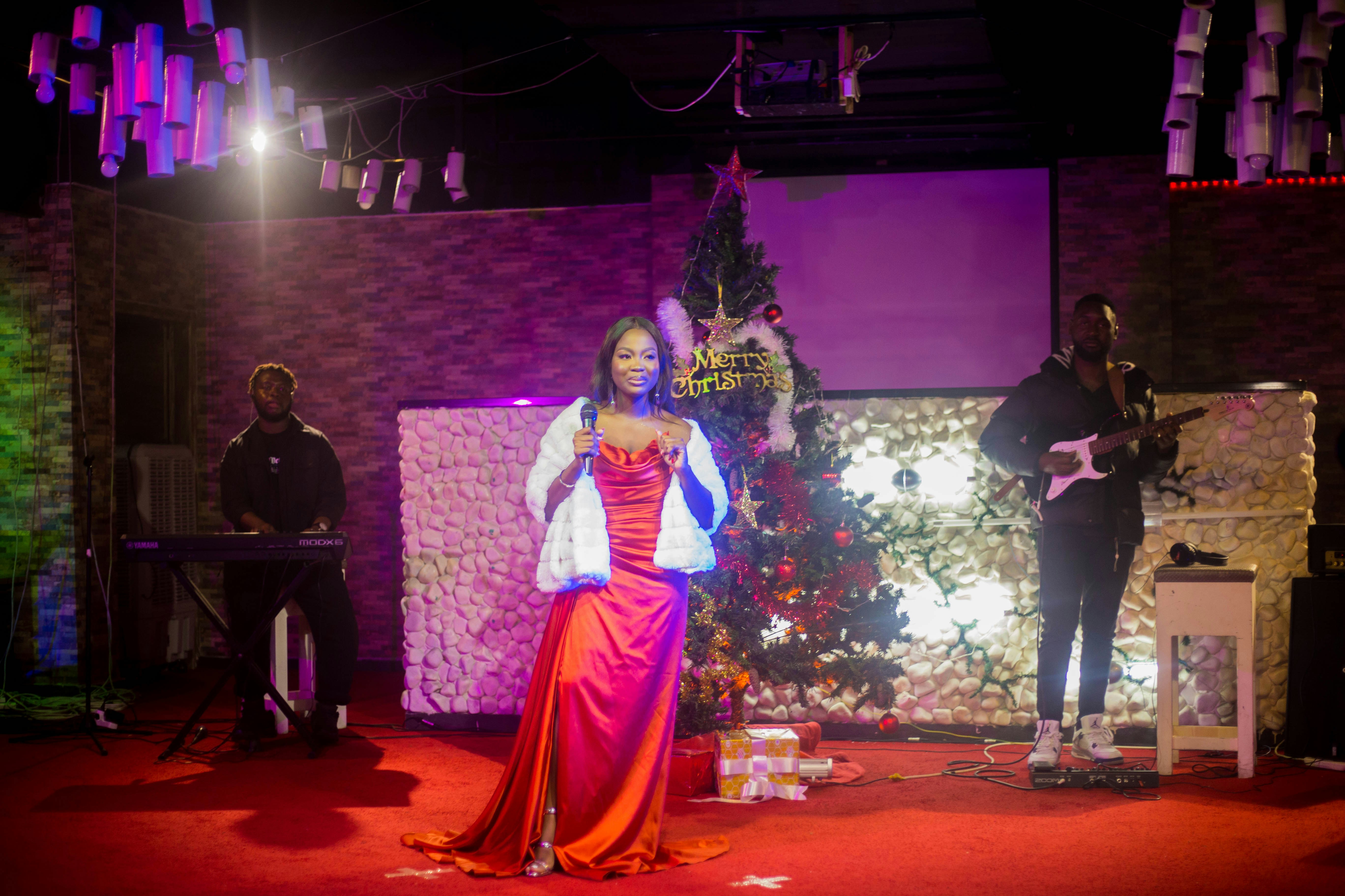 Woman in red dress singing on stage with band