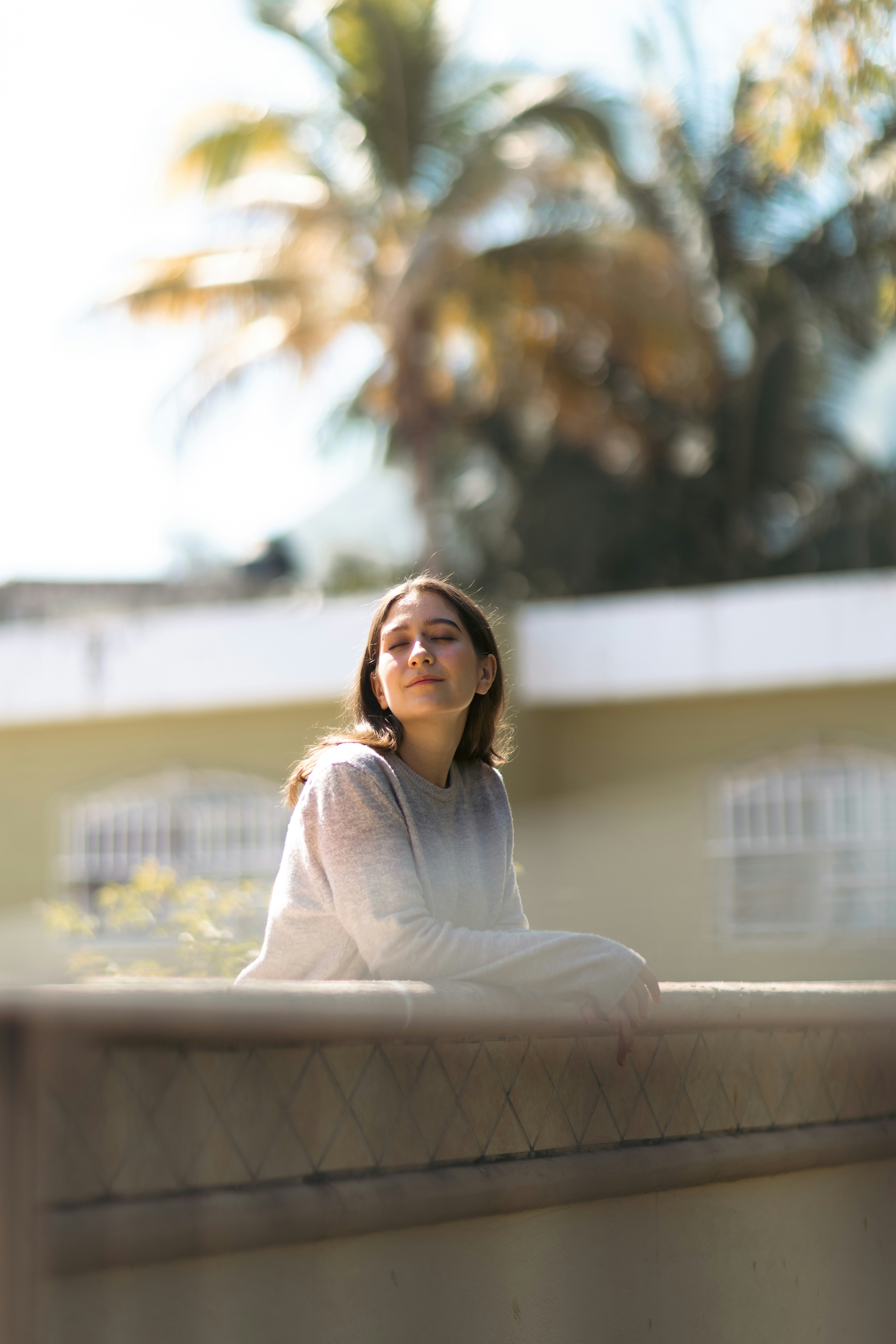 A woman sits with eyes closed, enjoying the sun.