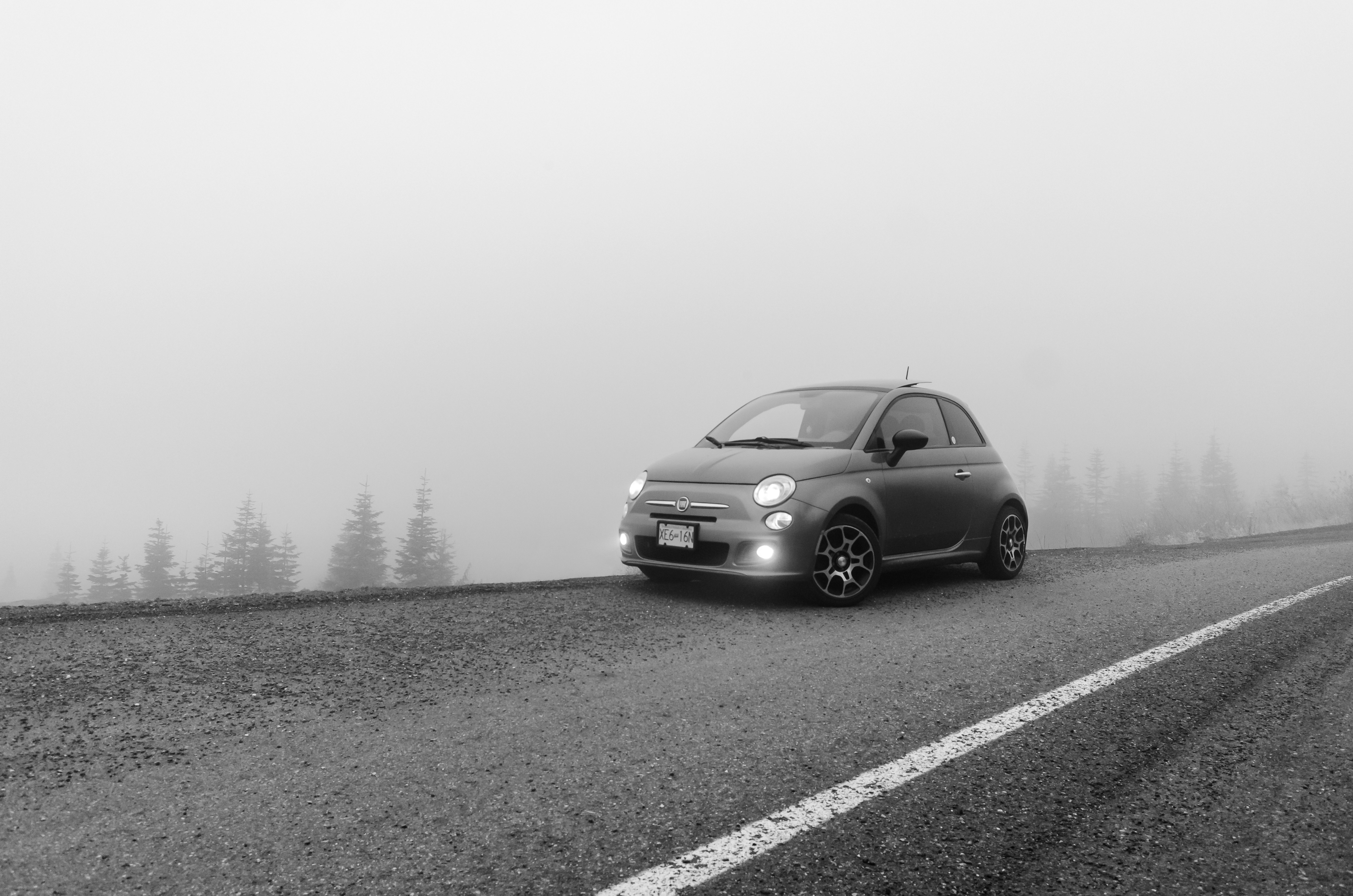 A small car drives on a foggy road