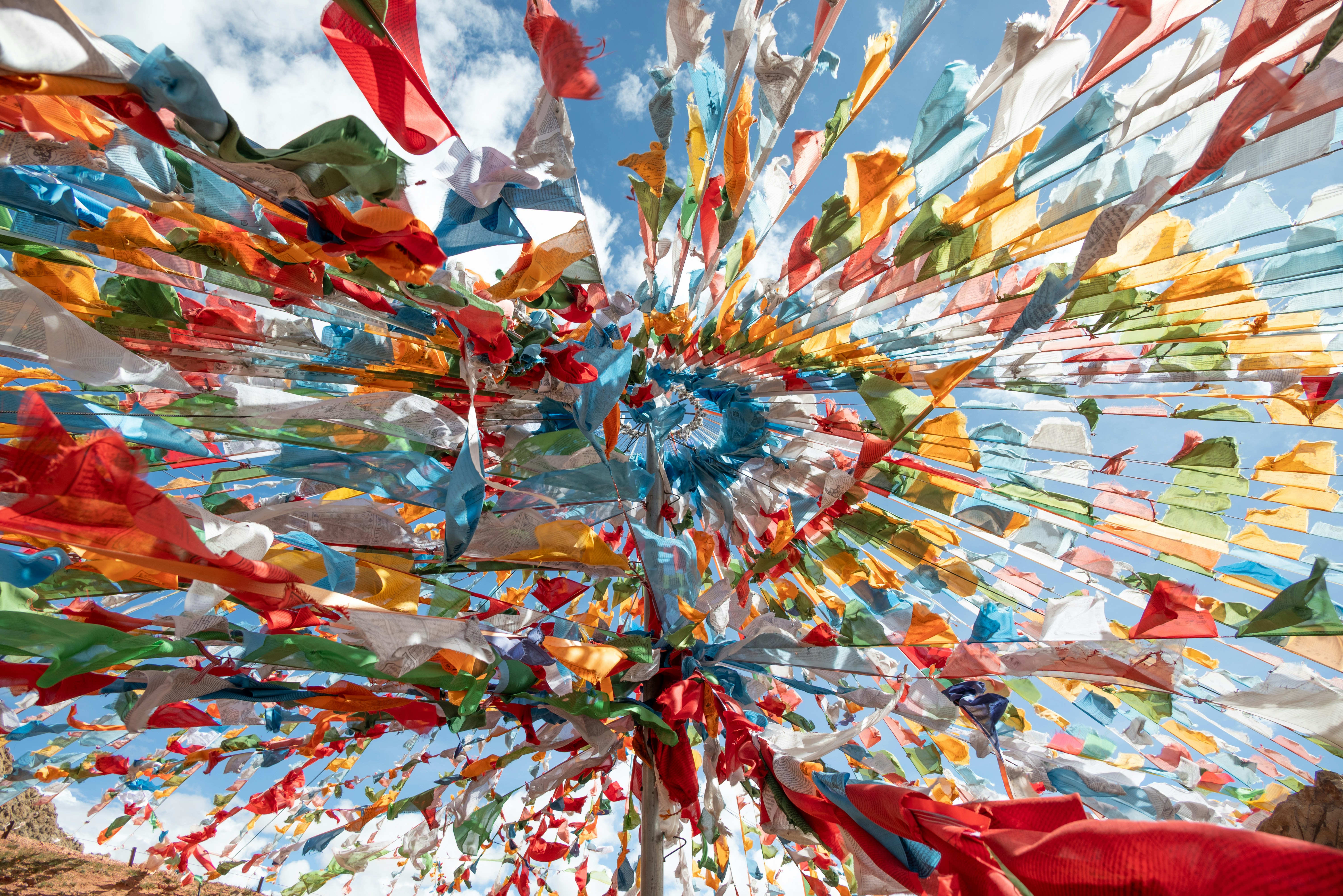 Colorful prayer flags flutter against a bright blue sky.
