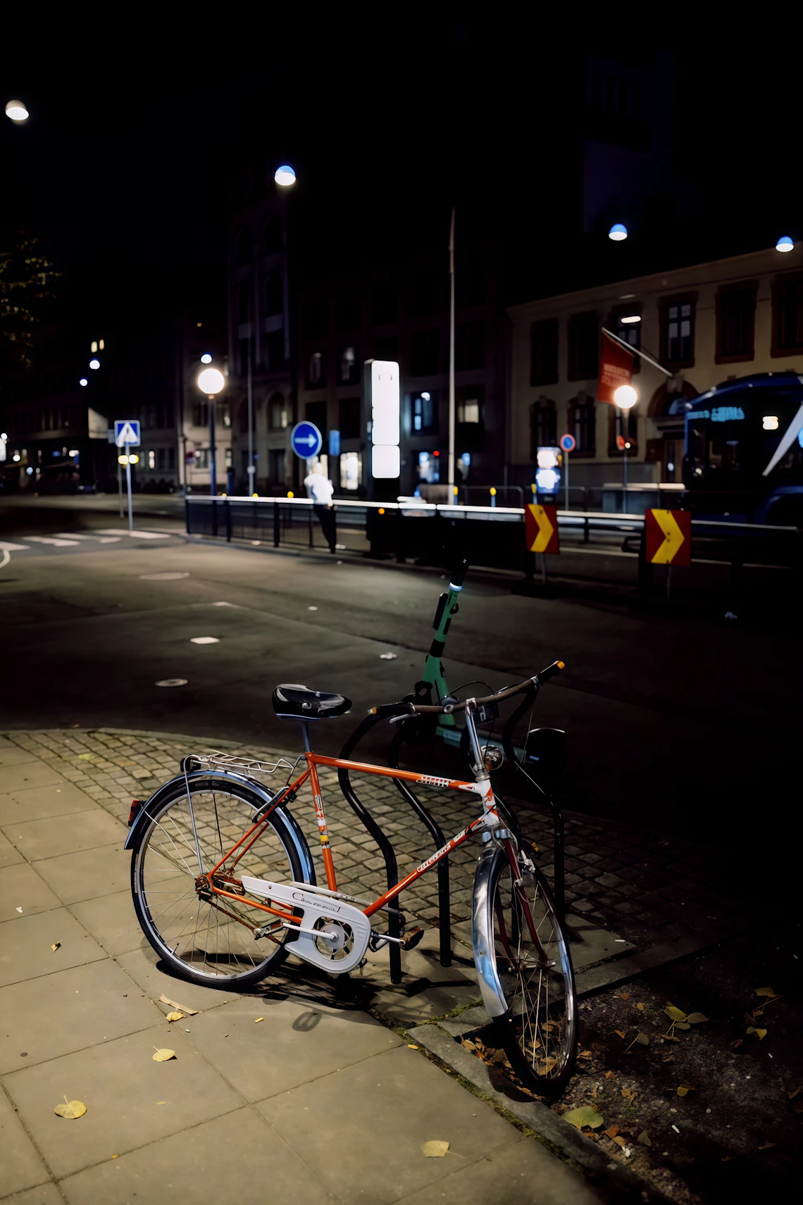 Bicycle parked on a city street at night under urban lights