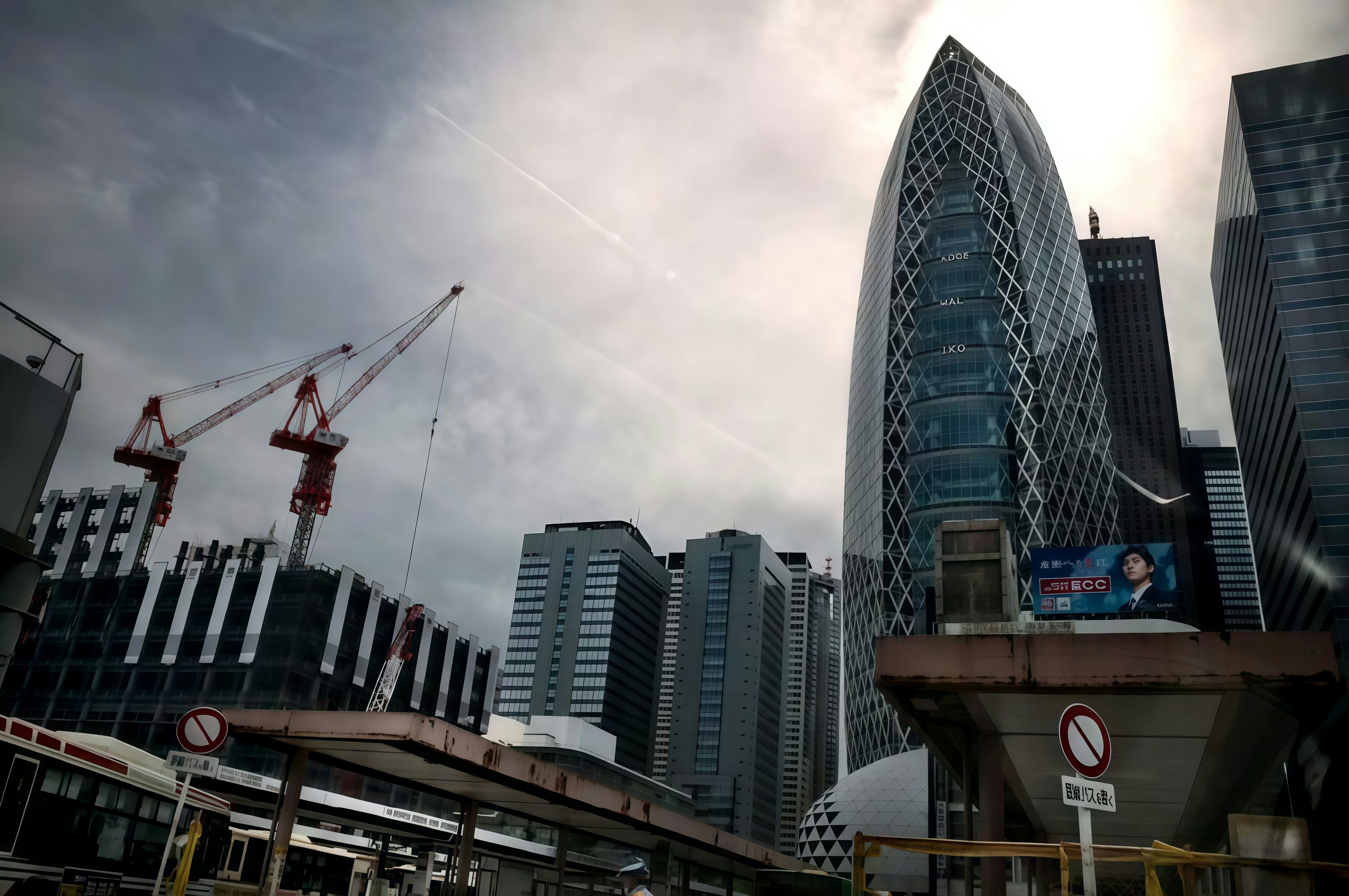 Modern skyscrapers and construction cranes under cloudy sky
