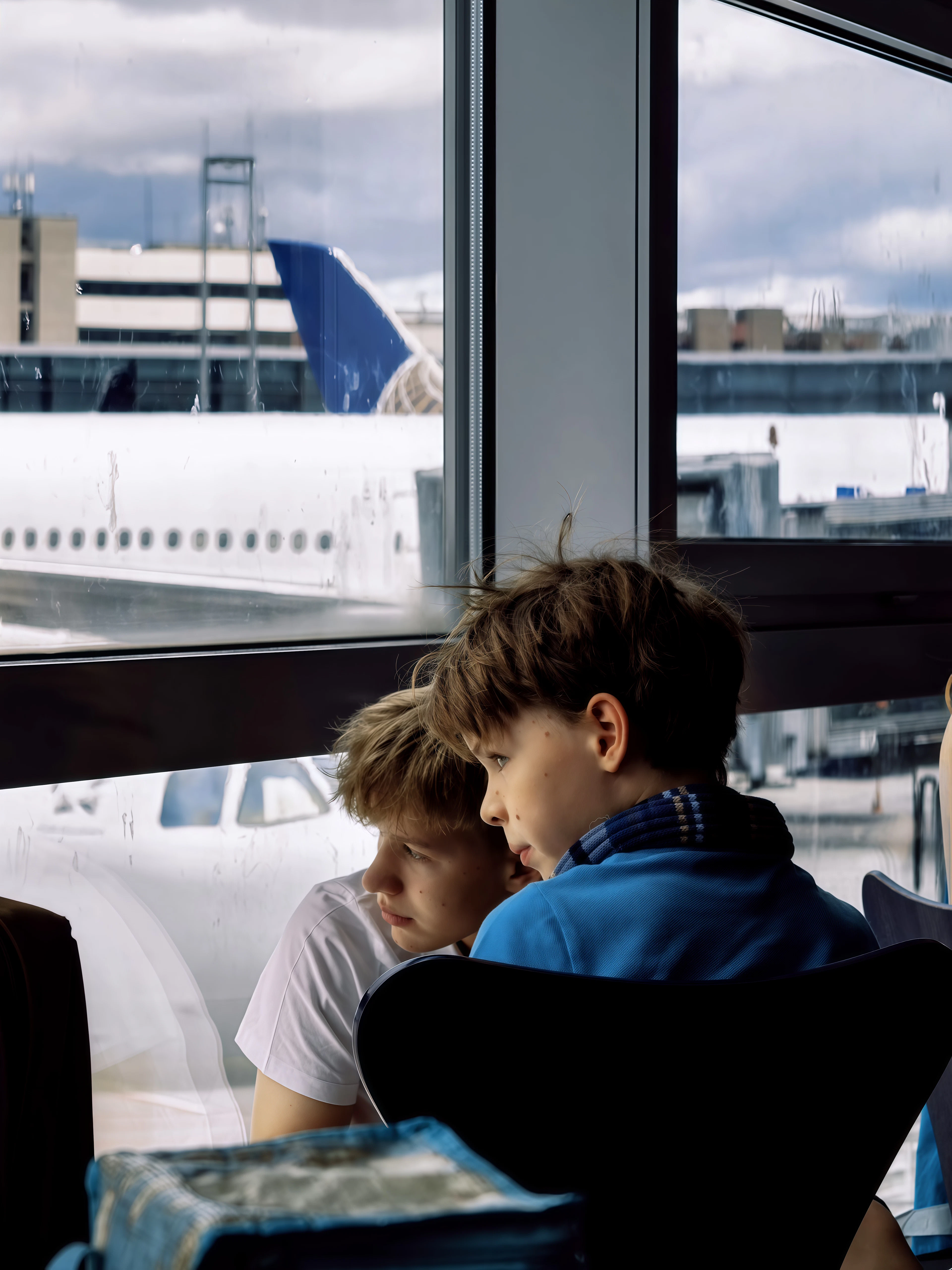 Two boys watching planes through an airport window