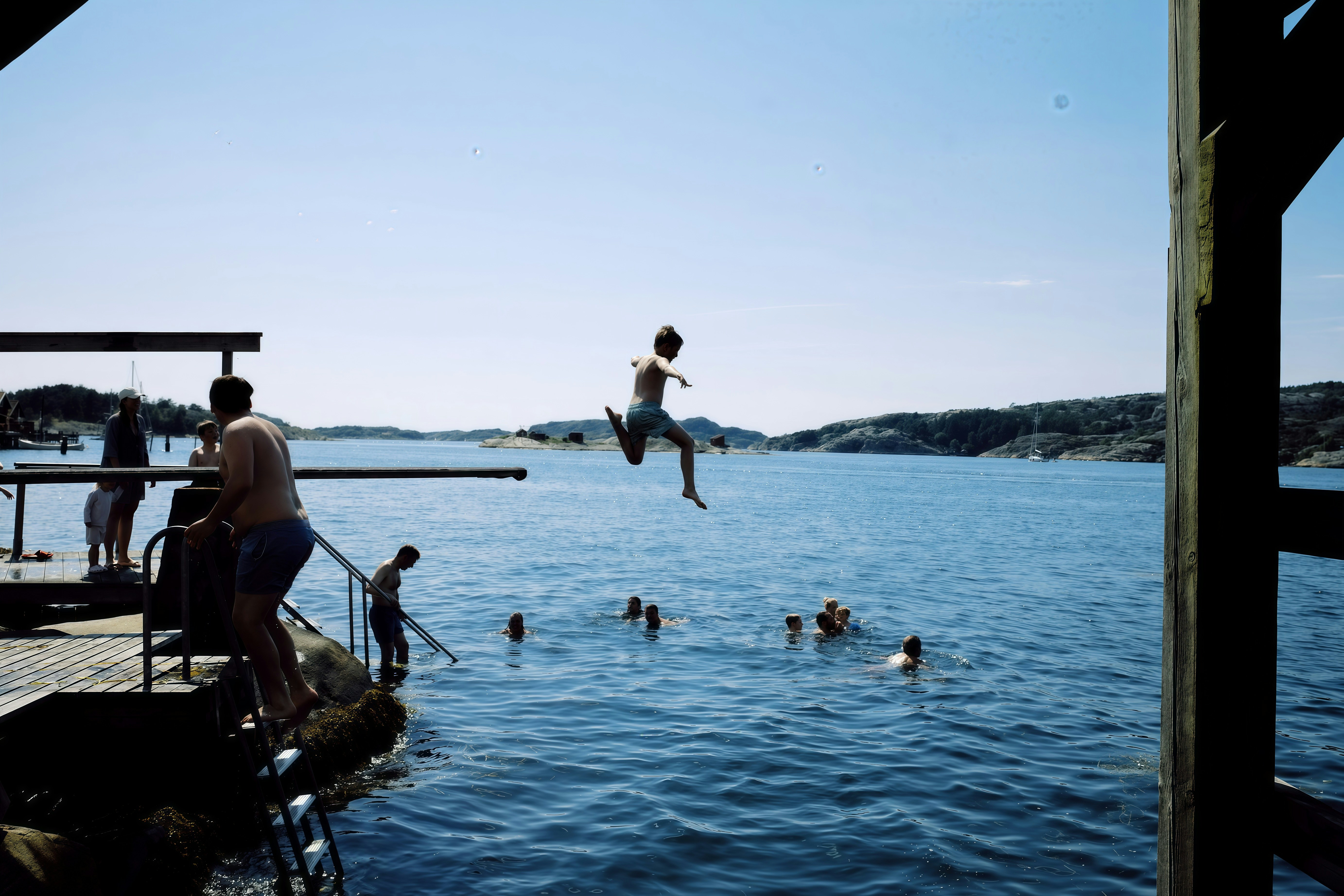 People jumping and swimming in clear blue water