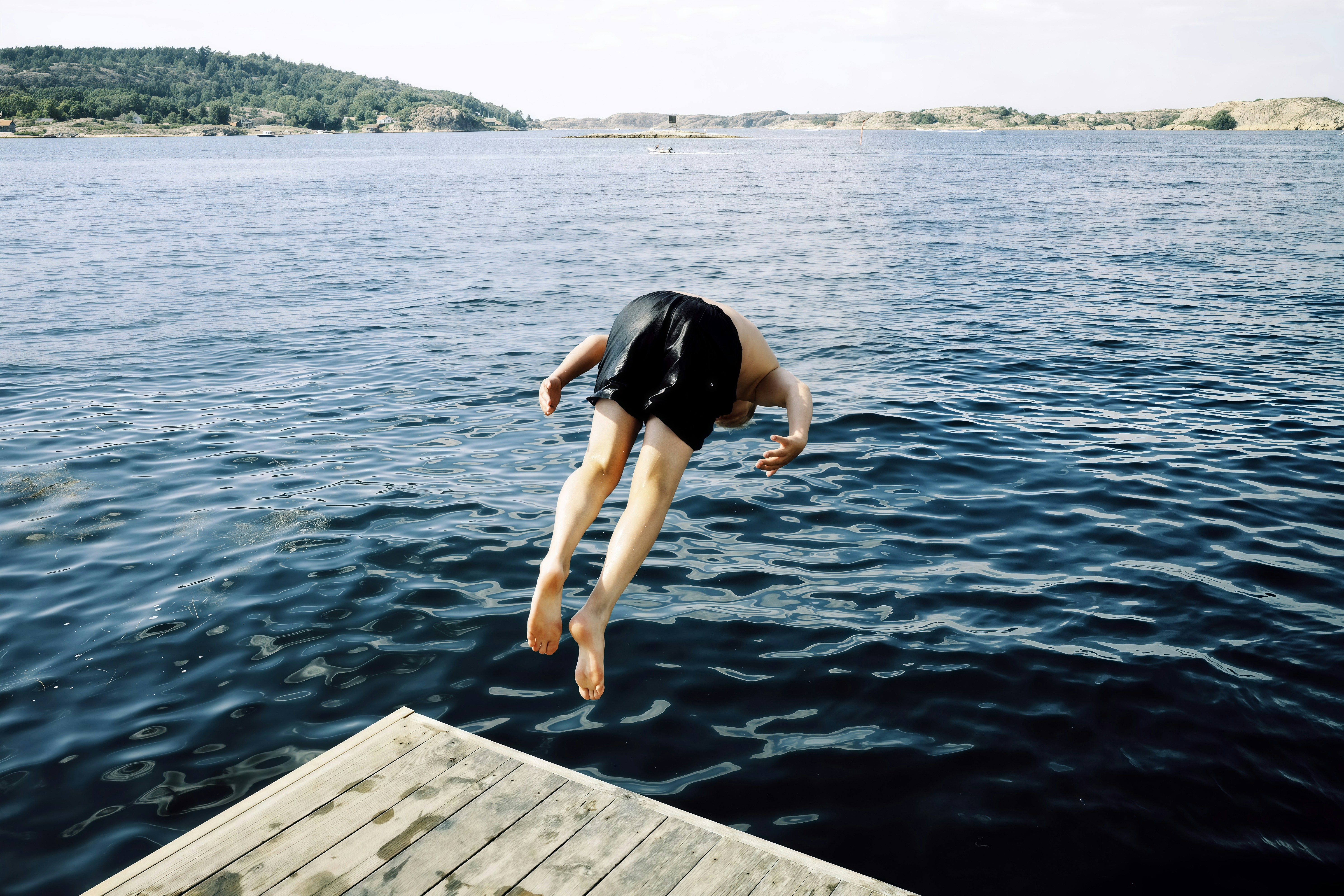 Person diving into the blue ocean from a wooden dock